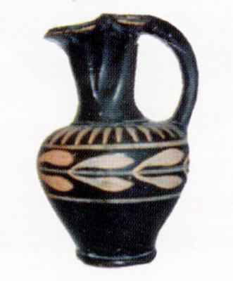 <i>Oinochoe</i> alta cm 11 con il labbro trilobato e decorazione centrale a rami di ulivo. Reperto della tomba 1. (dal v
